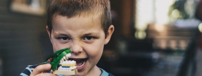 a child holding a lego model of a dinosaur mouth