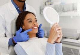 dental patient looking at the results of their dental treatment in a mirror while sitting in the dentists chair